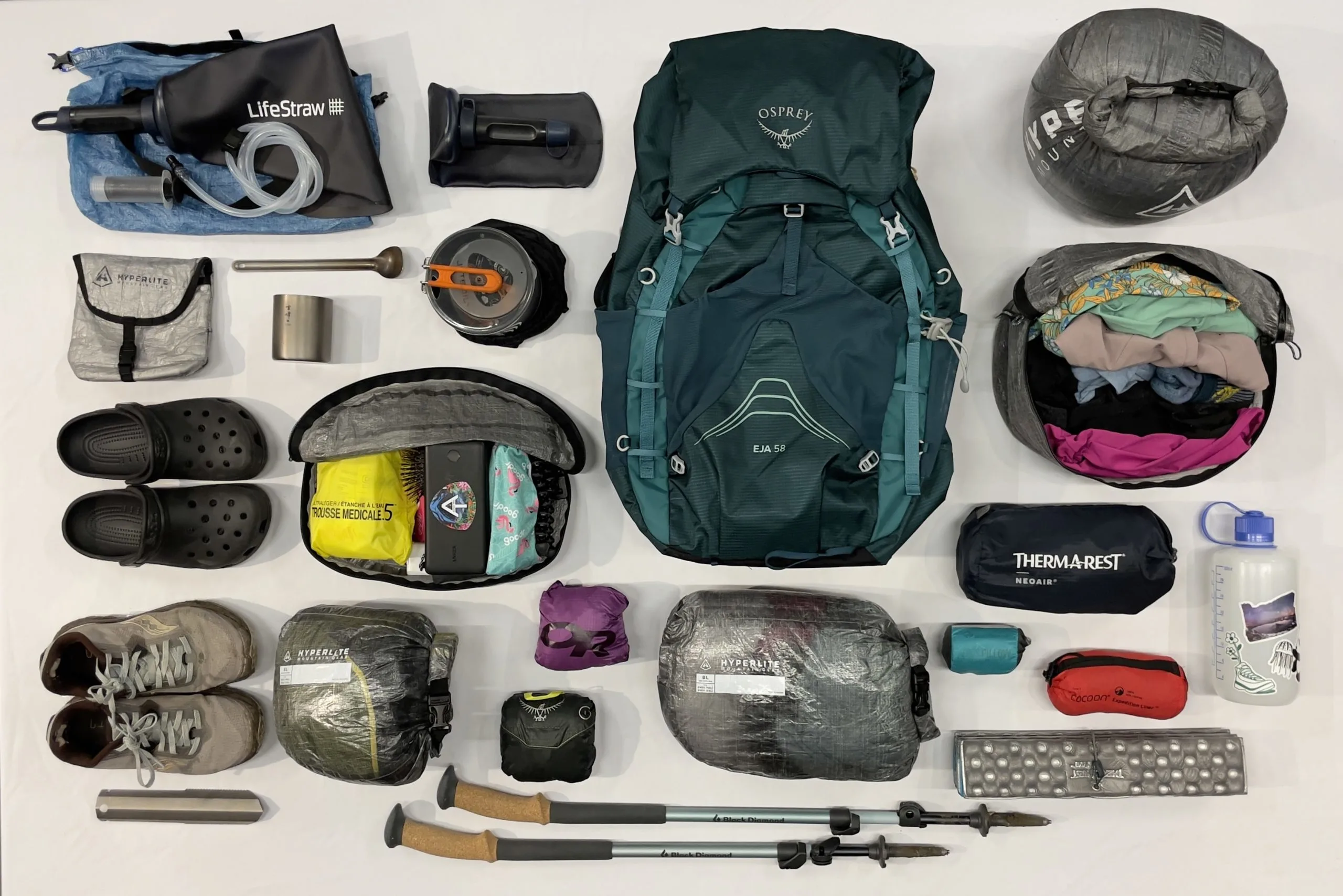Hiking gear laid out including backpack, boots, and trekking poles