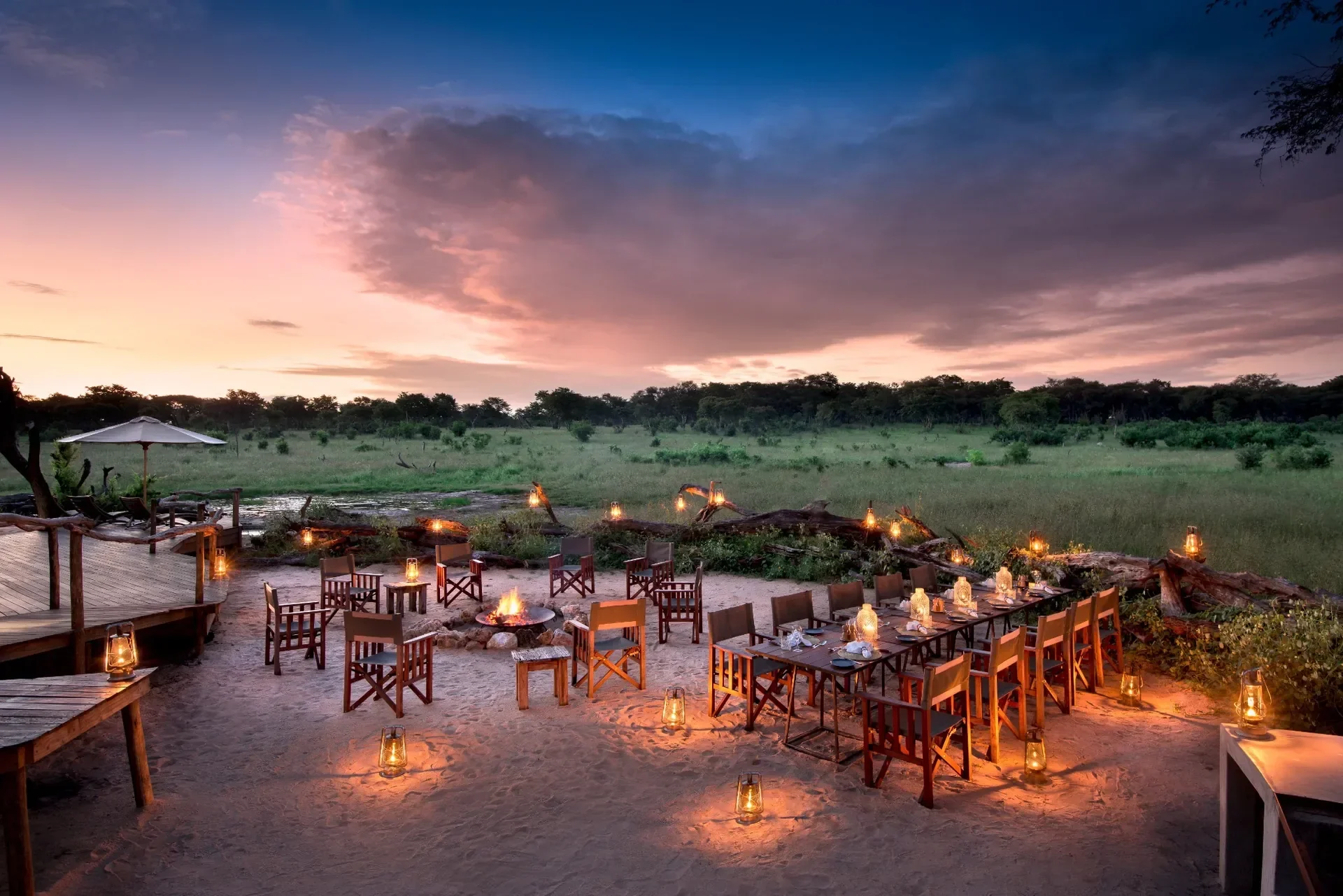 Private lantern-lit bush dinner table set up on safari
