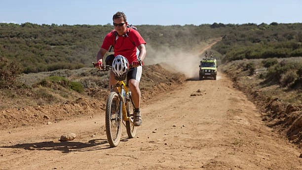 A 4x4 safari support vehicle following a group of mountain bikers for safety during an active wildlife cycling tour