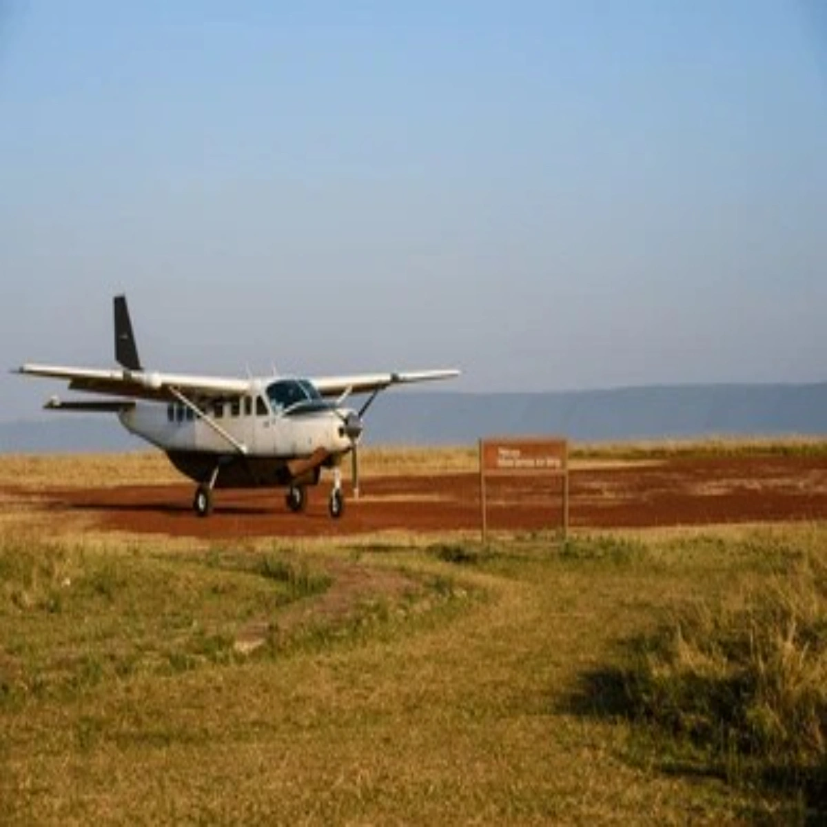 Light safari bush plane parked at a remote dirt airstrip in Kenya for internal transfers.